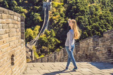 Happy cheerful joyful tourist woman at Great Wall of China having fun on travel smiling laughing and dancing during vacation trip in Asia. Girl visiting and sightseeing Chinese destination clipart