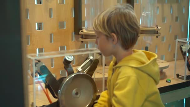 Slowmotion βολή από ένα μικρό αγόρι που επισκέπτονται ένα μουσείο επιστήμης για τα παιδιά. Αυτός συμπιέζει αέρα με μια αντλία χειρός, προκειμένου να καταστεί ένα πλαστικό μπουκάλι που πετούν επάνω — Αρχείο Βίντεο