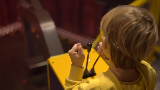 Fotografía en cámara lenta de un niño visitando un museo de ciencias para niños. Chico juega con un modelo de una excavadora. Niños probando diferentes profesiones concepto — Vídeo de stock