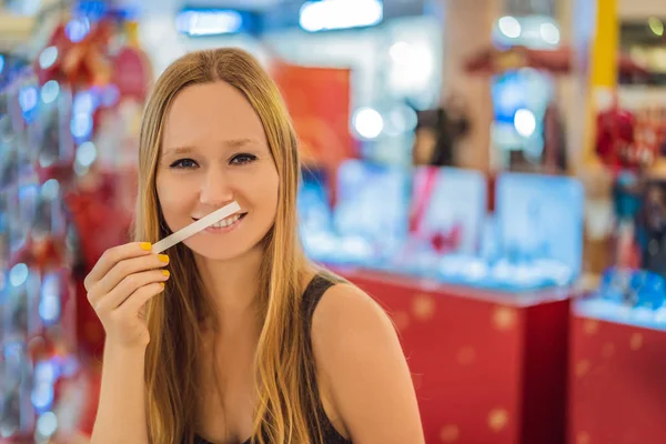 A woman with paper strips in her hands listens to the fragrance in the mall — Stock Photo, Image