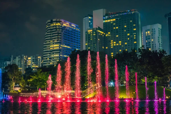 La colorida fuente en el lago por la noche, cerca de las Torres Gemelas con la ciudad en el fondo. Kuala Lumpur, Malasia —  Fotos de Stock
