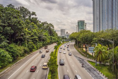 Karayolu ile gökdelenler ve yeşilliklerle çevrili arabalar