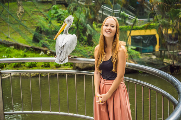 A young woman is photographed with a pelican. Great white pelican also known as the eastern white pelican, rosy or white pelican Pelecanus onocrotalus