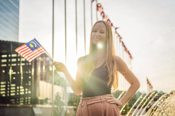 Young woman travels in Malaysia. Holds the Malaysian flag