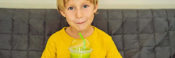 Le garçon boit du latte au thé vert avec de la glace dans un bocal à maçon. Thé Matcha Latte glacé maison avec lait zéro déchet BANNER, FORMAT LONG — Photo