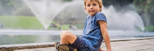 Boy on background of Fountain on the lake in the evening, near by Twin Towers with city on background. Kuala Lumpur, Malaysia BANNER, LONG FORMAT — Stock Photo, Image