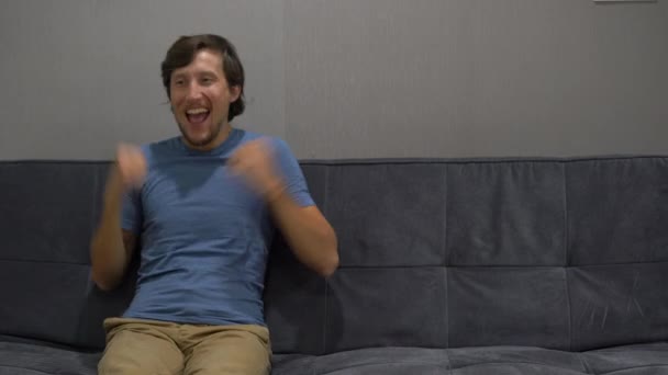 Young man sitting on a couch feeling happy and excited. Copy space on a right side — Stock Video