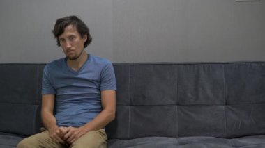 Genç bir adam bir kanepede oturuyor ve hissediyor hayal kırıklığına uğramış, depresif ve korku. Kopya alanı sağ tarafında