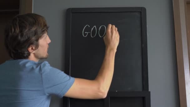 Närbild skott av en ung mn som ritar ett Godmorgon kära meddelande på svarta tavlan — Stockvideo