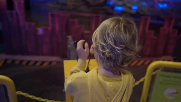 Slowmotion shot of a little boy visiting a science museum for children. Boy plays with a model of an excavator. Children trying different professions concept — Stock Video