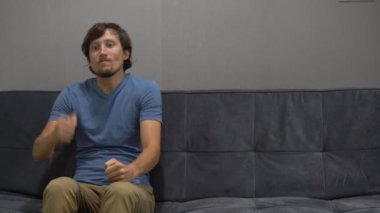 Genç bir adam bir kanepede oturuyor ve stres ve öfke hissediyor. Kopya alanı sağ tarafında