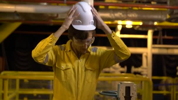 Genç adam sarı çalışma üniforma, gözlük ve kask endüstriyel ortamda petrol platformu veya sıvılaştırılmış gaz tesisi. Slowmotion atış — Stok video