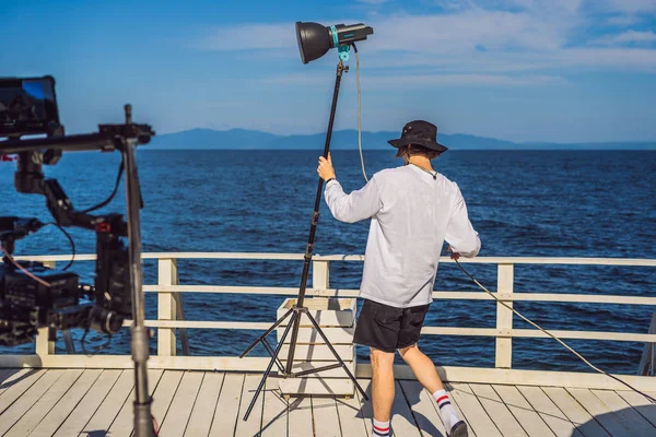 Gaffer o il capo elettricista in un'unità di produzione cinematografica o televisiva impostare le luci e la luce stand su uno scatto commerciale — Foto Stock