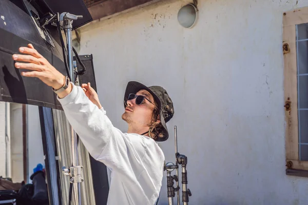 El gaffer o el electricista jefe en una unidad de producción cinematográfica o televisiva instala las luces y el soporte luminoso en un rodaje comercial — Foto de Stock