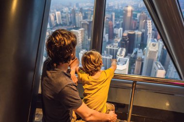 Baba ve oğlu Kuala lumpur cityscape arıyoruz. Gün batımı gökdelenler içinde Malaysia bina panoramik manzaraya Kuala Lumpur şehir manzarası akşam. Çocuklar kavramı ile seyahat