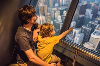 Baba ve oğlu Kuala lumpur cityscape arıyoruz. Gün batımı gökdelenler içinde Malaysia bina panoramik manzaraya Kuala Lumpur şehir manzarası akşam. Çocuklar kavramı ile seyahat