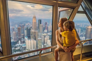 Anne ve oğlu Kuala lumpur cityscape arıyoruz. Gün batımı gökdelenler içinde Malaysia bina panoramik manzaraya Kuala Lumpur şehir manzarası akşam. Çocuklar kavramı ile seyahat