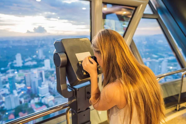 Anya és fia keres Kuala lumpur városkép. Használata távcsövek. Panorámás kilátással Kuala Lumpur city skyline este naplemente felhőkarcolók látványát, épület Malajzia. Utazótáska-val kids koncepció — Stock Fotó