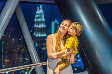 Anne ve oğlu Kuala lumpur cityscape arıyoruz. Gün batımı gökdelenler içinde Malaysia bina panoramik manzaraya Kuala Lumpur şehir manzarası akşam. Çocuklar kavramı ile seyahat