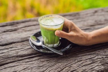 Kadın el holding matcha Latte, yeşil çay, eski ahşap arka plan masada fincan.