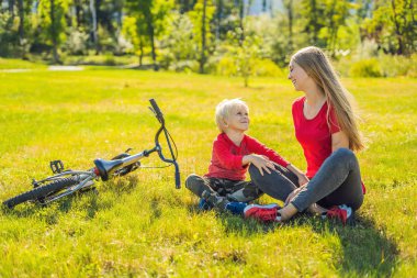 Anne ve oğlu çimenlerin üzerinde bisiklete binmek sonra dinlenme