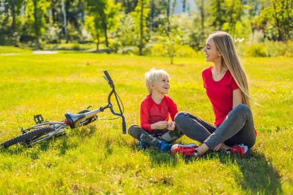 Anne ve oğlu çimenlerin üzerinde bisiklete binmek sonra dinlenme — Stok fotoğraf