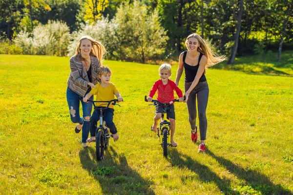 Две Счастливые Матери Учат Своих Счастливых Сыновей Кататься Велосипеде — стоковое фото