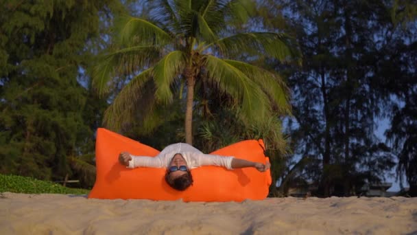 Fotografía en cámara lenta de un joven divirtiéndose en un sofá inflable en una hermosa playa — Vídeo de stock