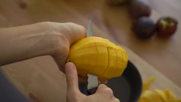 4x times Slowmotion shot of a young woman cutting the mango into cubes and lots of tropical fruits lay on a table — Stock Video