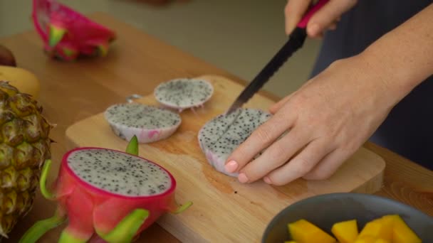 2x vezes Slowmotion tiro de uma jovem mulher cortando a fruta do dragão em cubos e muitas frutas tropicais estavam em uma mesa — Vídeo de Stock