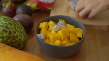 4 x Slowmotion shot dragon meyve küpleri bir gri seramik kasenin içine koyarak bir genç kadının kez ve tropikal meyve bir sürü bir açayım