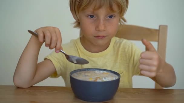 Superslowmotion tiro de um menino comendo uma tigela de batido de banana com frutas de dragão, manga, granola, passas, fatias de amêndoa, e sementes de chia — Vídeo de Stock