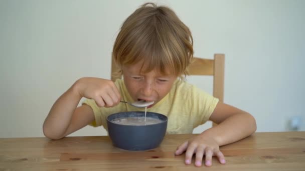 Superslowmotion tiro de um menino comendo uma tigela de batido de banana com frutas de dragão, manga, granola, passas, fatias de amêndoa, e sementes de chia — Vídeo de Stock