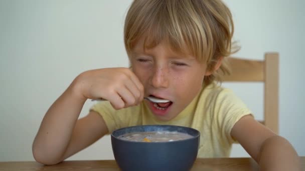 Superslowmotion tiro de um menino comendo uma tigela de batido de banana com frutas de dragão, manga, granola, passas, fatias de amêndoa, e sementes de chia — Vídeo de Stock