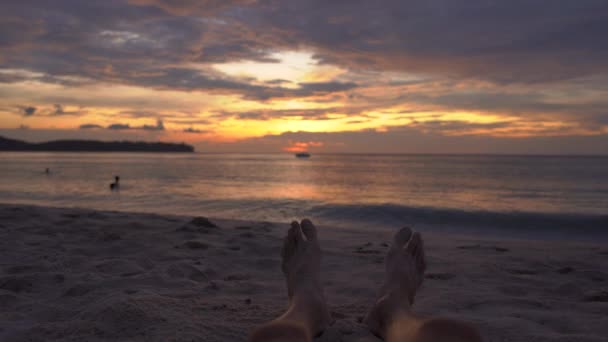 Piernas de un hombre en una playa viendo una puesta de sol fantástica — Vídeo de stock