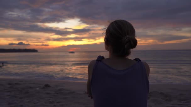 Mujer joven en una playa viendo una puesta de sol fantástica — Vídeo de stock