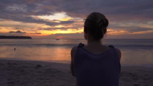 Jeune femme sur une plage regardant un coucher de soleil fantastique — Video