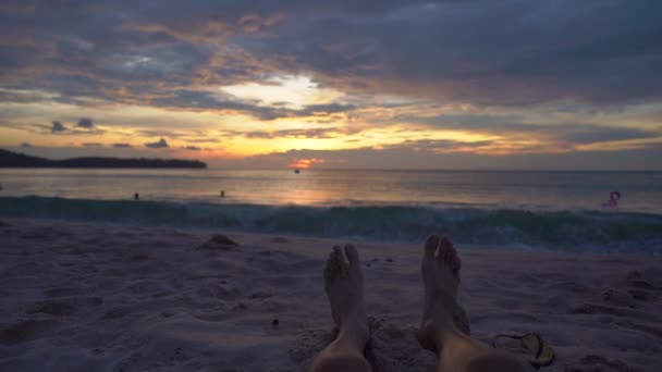 El tiro en cámara lenta - las piernas de una mujer en una playa viendo una puesta de sol fantástica — Vídeos de Stock