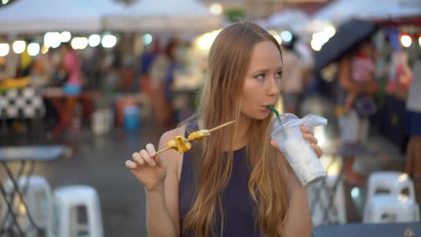 Slowmotion πλάνο της σε μιας νεαρής γυναίκας που τρώει το φαγητό του δρόμου σε μια ασιατική αγορά — Αρχείο Βίντεο