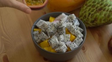 Slowmotion atış kesme tutku meyve dragon meyve ve manfo küpleri ve çok tropikal meyve bir kase içine koyarak bir genç kadının bir açayım