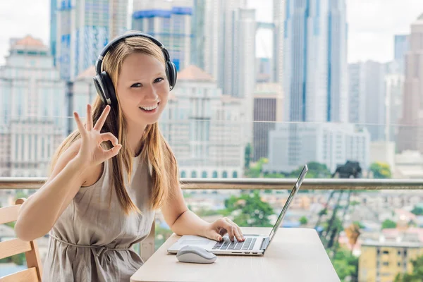 Young woman teaches a foreign language or learns a foreign language on the Internet on her balcony against the backdrop of a big city. Online language school lifestyle — Stock Photo, Image