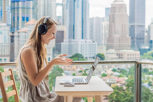 Tânăra predă o limbă străină sau învață o limbă străină pe internet pe balconul ei pe fundalul unui oraș mare. Stilul de viață școlar online — Fotografie, imagine de stoc