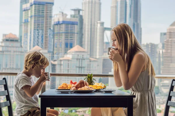 Щаслива сім'я снідала на балконі. Сніданок з кавовими фруктами та хлібом на балконі на тлі великого міста — стокове фото