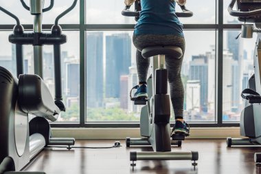 Bir büyük şehir arka planda sabit bir bisiklet bir spor salonunda genç kadın