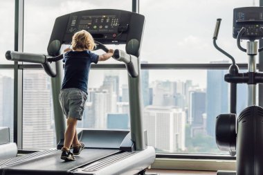 Küçük bir çocuk koşu bandı üzerinde çalışan. Çocuk spor kavramı