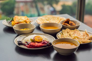 Koyu ahşap arka plan üzerinde çeşitli Hint yemeği. Yemekler ve mezeler Hint Mutfak. Köri, tereyağı tavuk, pirinç, mercimek, paneer, samosa, naan, Hint turşusu, baharatlar. Kase ve Hint yemekleri ile plakalar