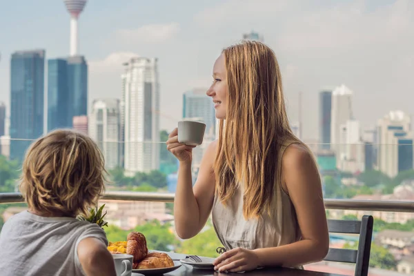 Щаслива сім'я снідала на балконі. Сніданок з кавовими фруктами та хлібом на балконі на тлі великого міста — стокове фото