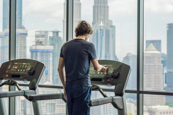 Man running in a gym on a treadmill against the background of a big city. concept for exercising, fitness and healthy lifestyle — Stock Photo, Image