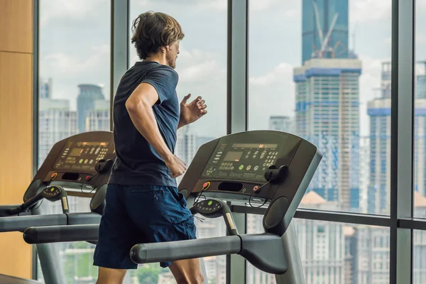 Man running in a gym on a treadmill against the background of a big city. concept for exercising, fitness and healthy lifestyle — Stock Photo, Image