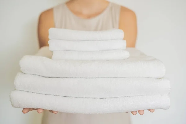 A woman is holding a stack of white towels. Concept of service in hotels, laundry, spa — Stock Photo, Image